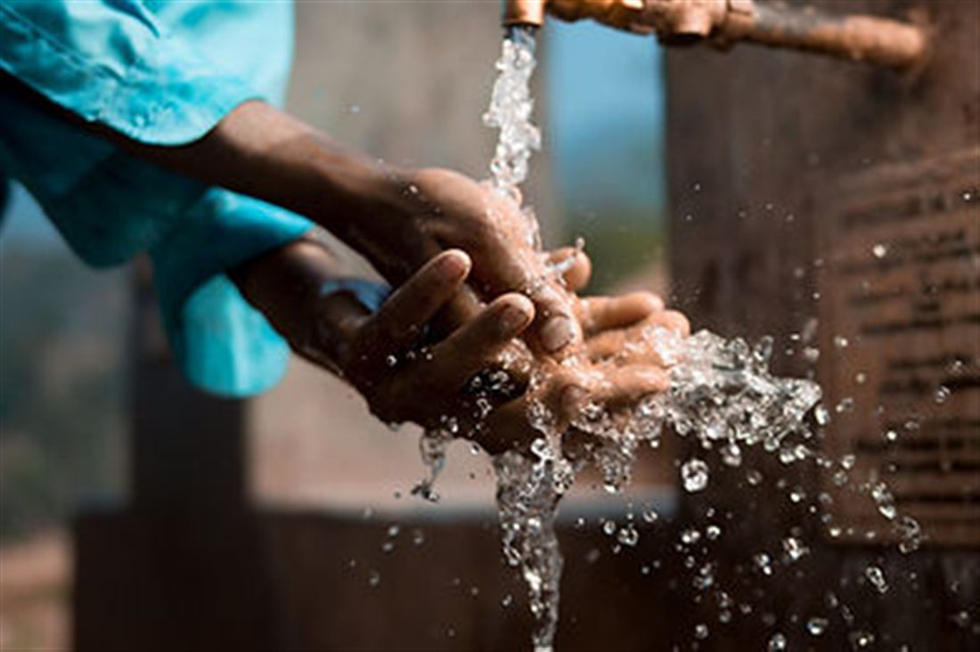 Clean water flowing over a pair of hands at a village pump